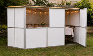 The Hard Wall Aluminium Sukkah with its door open in a garden
